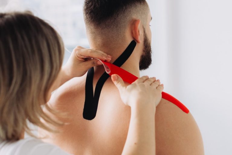 Eine Person verleiht einem Mann mit Tape Unterstützung am Nacken.