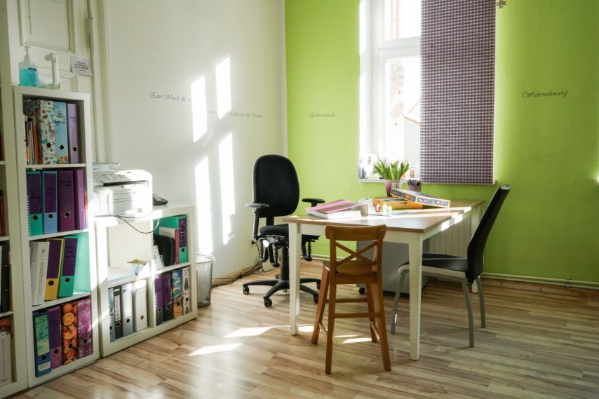 Heller, moderner Arbeitsraum mit einem Tisch, Stühlen und Regalen voller Unterlagen.