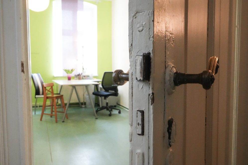 Ein offenes Zimmer mit grünen Wänden, einem Tisch und zwei Stühlen in Sicht.